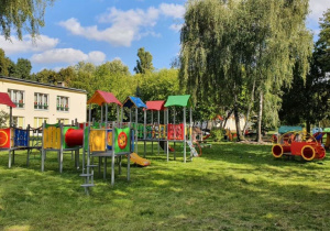 Ogród przedszkolny a w nim piękny, nowoczesny, kolorowy plac zabaw.